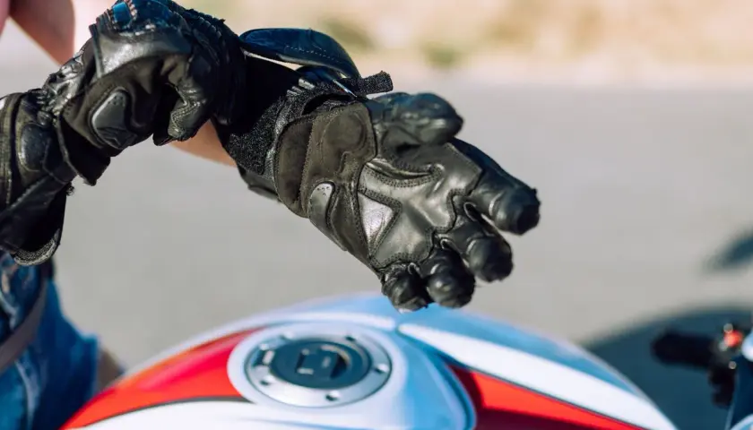Persona se ajusta guantes de moto negros. Es obligatorio llevar guantes en moto para protegerse.