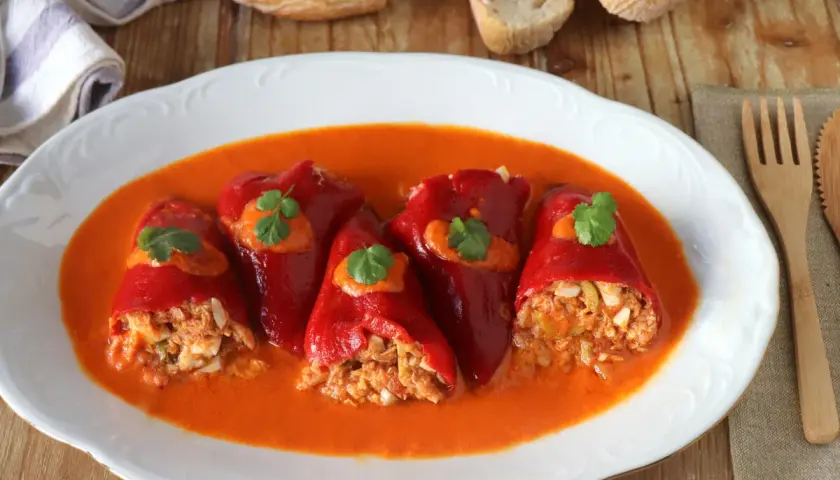Pimientos del piquillo rellenos de atún y huevo, bañados en una salsa de pimientos. Un plato casero listo para disfrutar.