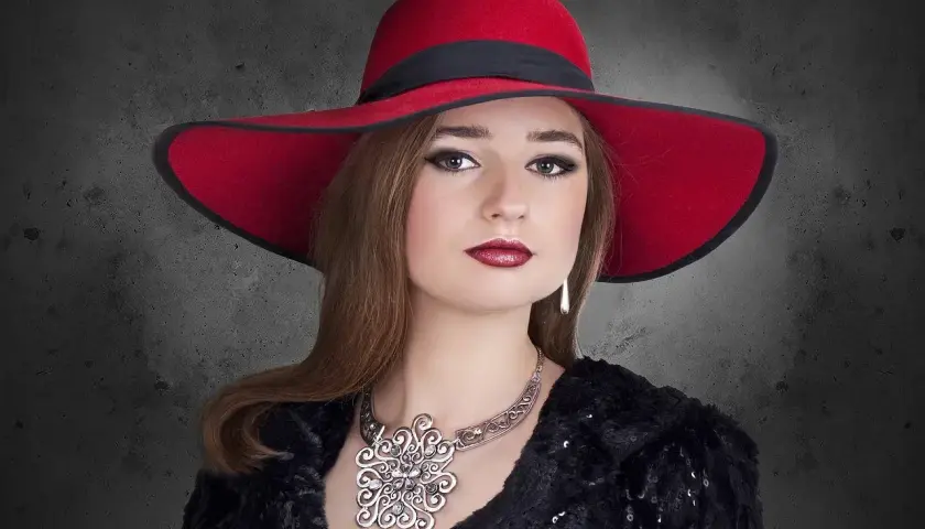 Elegancka kobieta w czerwonym kapeluszu i biżuterii, uosobienie stylu marki premium.