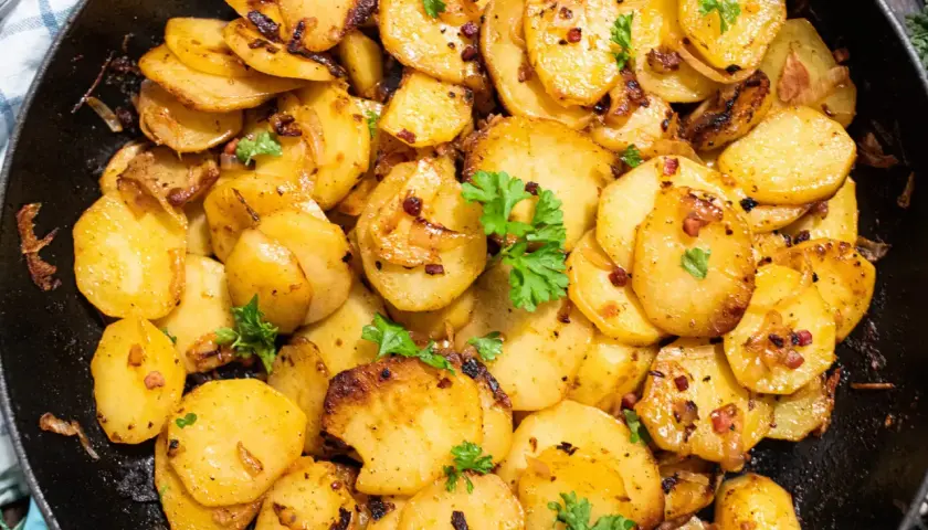Knusprige Bratkartoffeln aus rohen Kartoffeln, goldbraun gebraten mit Zwiebeln und Speck, garniert mit Petersilie. Ein Genuss!