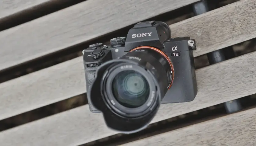 Sony A7 III test na drewnianej ławce. Aparat z obiektywem leży na deski.