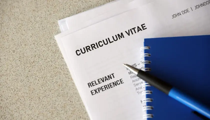 Długopis leży na dokumentach z nagłówkiem "CURRICULUM VITAE" i sekcją "RELEVANT EXPERIENCE". To klauzula CV po angielsku, gotowa do uzupełnienia.