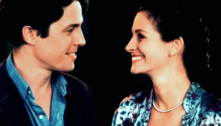 Uśmiechnięta obsada Notting Hill: Hugh Grant i Julia Roberts patrzą na siebie z czułością.