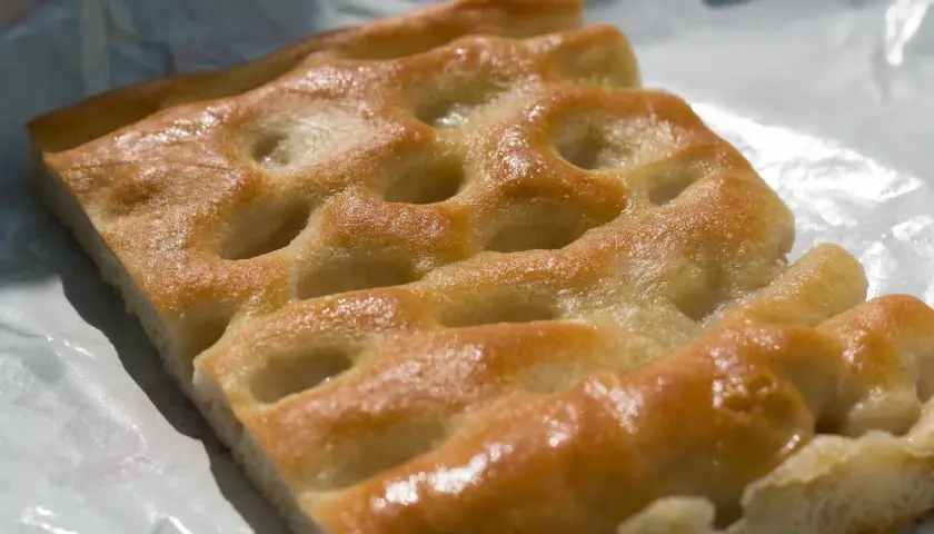 Focaccia genovese, un must per capire cosa mangiare a Genova. Dorata, soffice e profumata, perfetta da gustare in ogni momento.