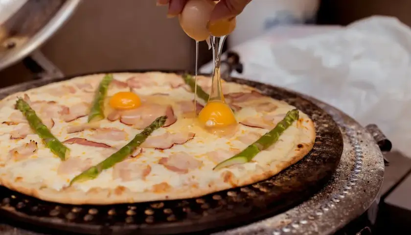 Na pizzę z boczkiem i szparagami dodawane jest jajko.