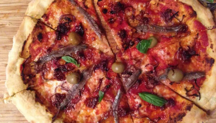 Pizza napolitana con anchoas, aceitunas y albahaca. Una delicia para disfrutar en cualquier momento.