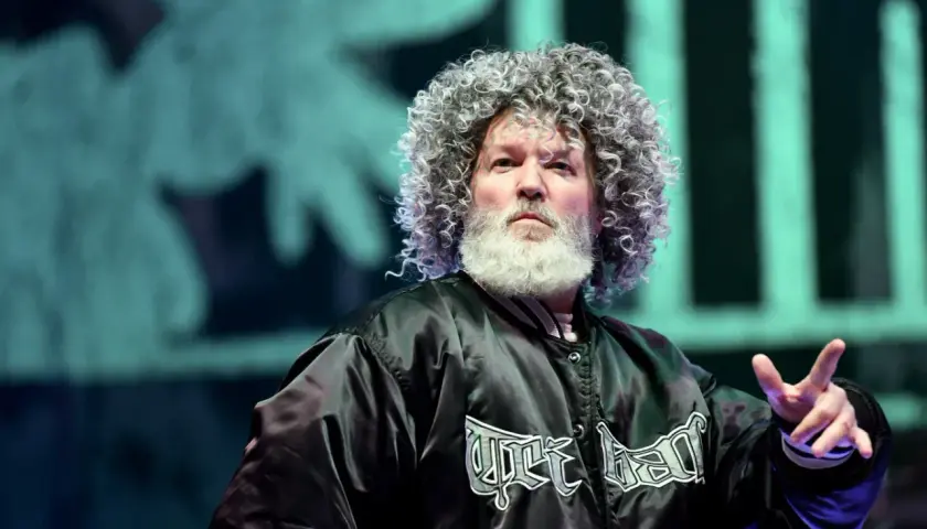 Fred Durst z Limp Bizkit na koncercie, z charakterystyczną fryzurą i brodą, w czarnej kurtce z logo zespołu.