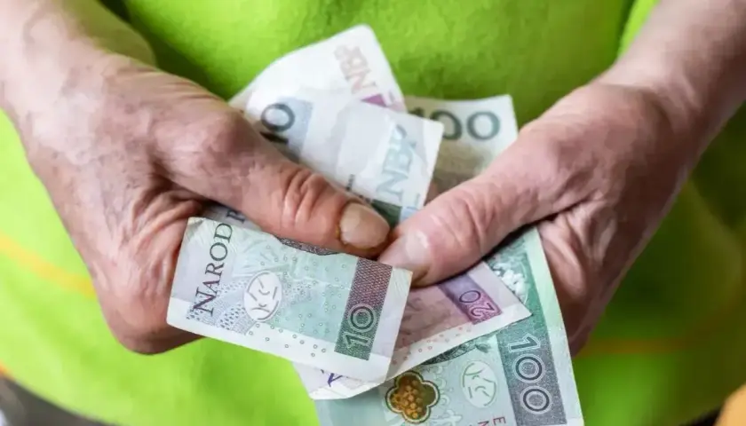 Dłonie trzymają polskie banknoty. Czy to już przyszła renta socjalna 2026?