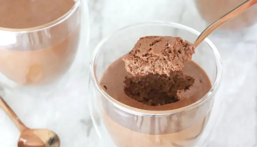 Une cuillère prélève une bouchée aérienne d'une mousse au chocolat onctueuse, parfaite la veille ou le jour même.