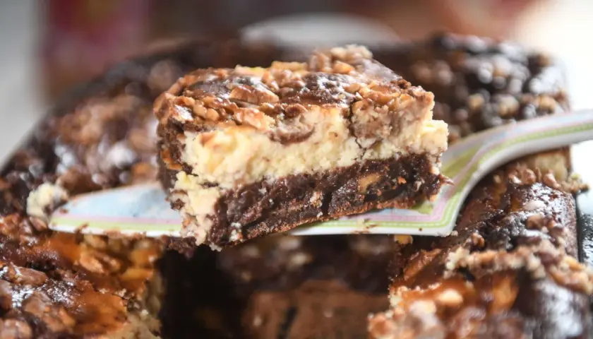 Ein Stück Schoko-Käsekuchen mit Walnüssen, der so gut aussieht, dass man ihn "friss dich dumm" nennen könnte.