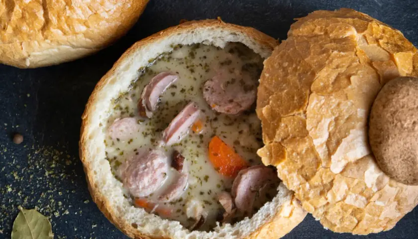 Pyszny żurek z jajkiem i kiełbasą podany w chlebie. Aromatyczne zioła i przyprawy podkreślają smak tradycyjnej polskiej zupy.