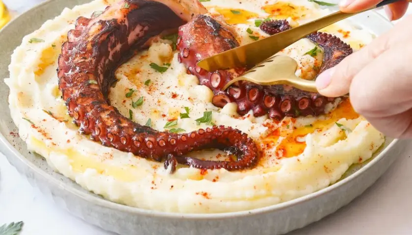 Un delicioso pulpo a la brasa, con sus tentáculos crujientes, servido sobre un puré cremoso.