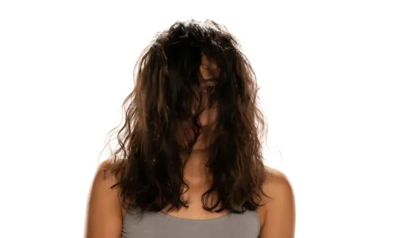 Frau mit dunklem, welligem Haar, das ihr Gesicht verdeckt. Ein Blick auf ihre Schultern und den Ansatz ihres Halses. Vielleicht ist dies das Ergebnis einer neuen locken routine.