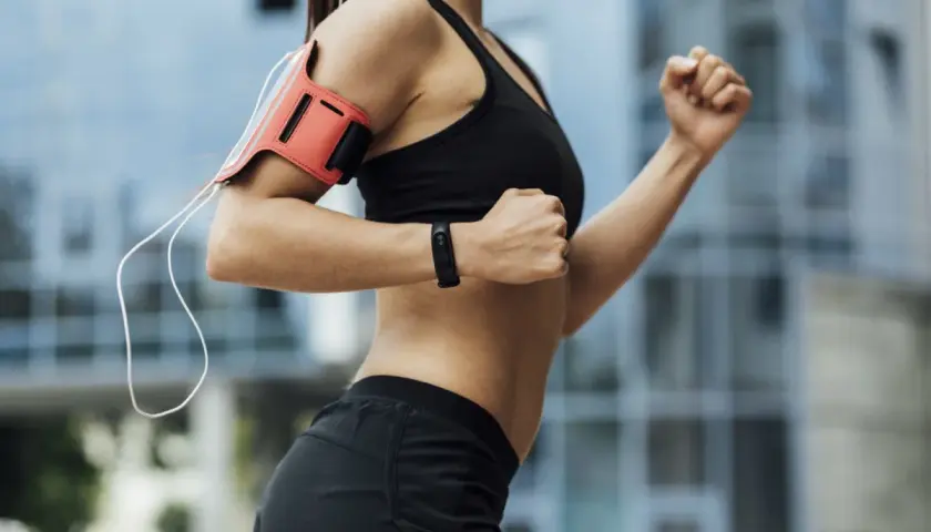 Kobieta w sportowym stroju biegnie, angażując liczne mięśnie. Widoczne ramiona, brzuch i nogi pracują intensywnie.