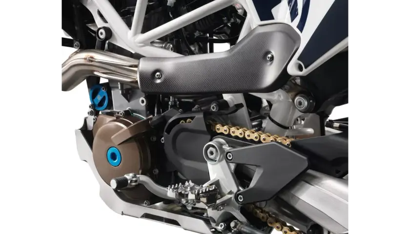 Szczegółowy widok silnika motocykla Husqvarna z widoczną złotą kasetą i elementami układu napędowego.