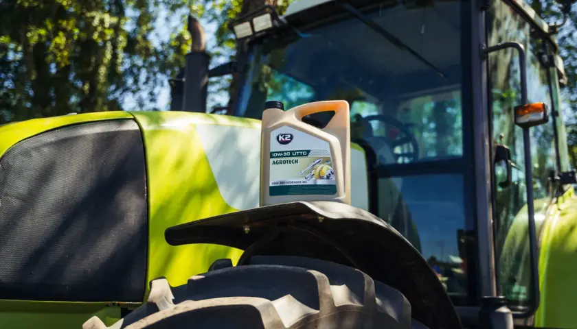 Kanister oleju K2 AGROTECH 10W-30 UTTO na błotniku zielonego traktora.