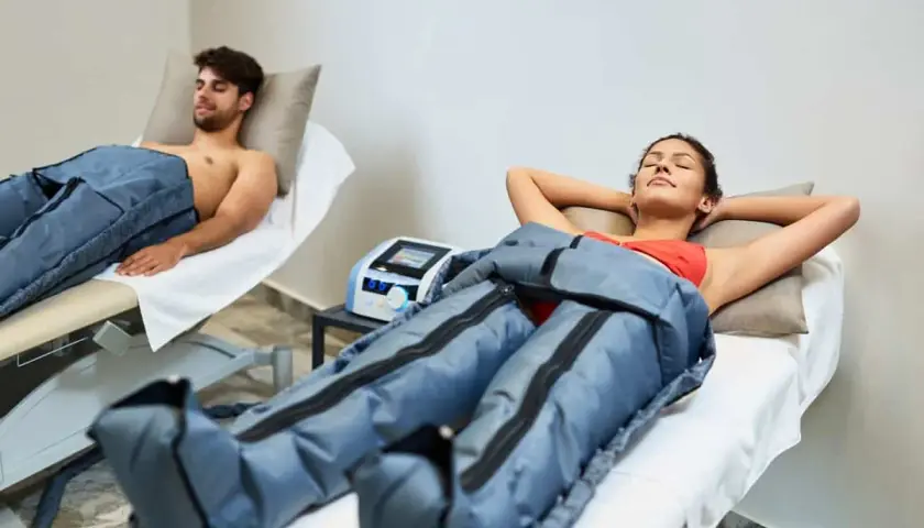 Dos personas disfrutan de la presoterapia, un tratamiento para mejorar la circulación y reducir la hinchazón.