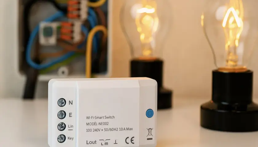 Interruptor Wi-Fi inteligente junto a bombillas encendidas y caja de conexiones.