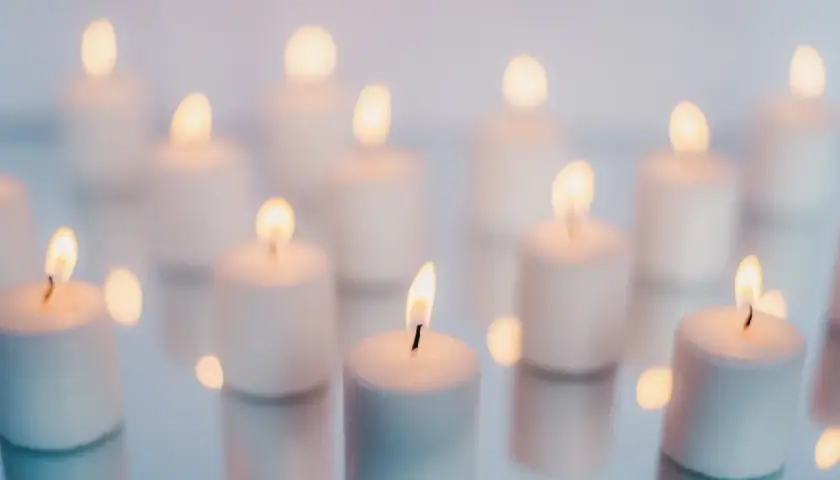 Wiele białych świec płonie na lustrzanej powierzchni. Zielona świeca znaczenie symbolizuje nadzieję i odnowę.