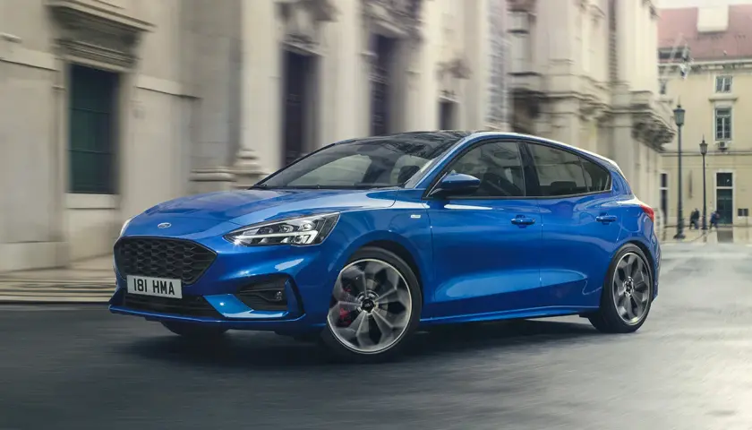 Ford Focus blu in movimento, disponibile con motori a benzina e diesel, sfreccia in una strada cittadina.