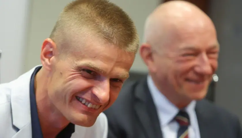 Uśmiechnięty Tomasz Komenda, który otrzymał ogromne odszkodowanie za niesłuszne skazanie, siedzi obok drugiego mężczyzny.