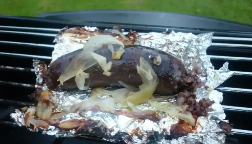 Kaszanka z grilla, soczysta i aromatyczna, pieczona na folii aluminiowej z cebulką. Idealna na letnie wieczory.