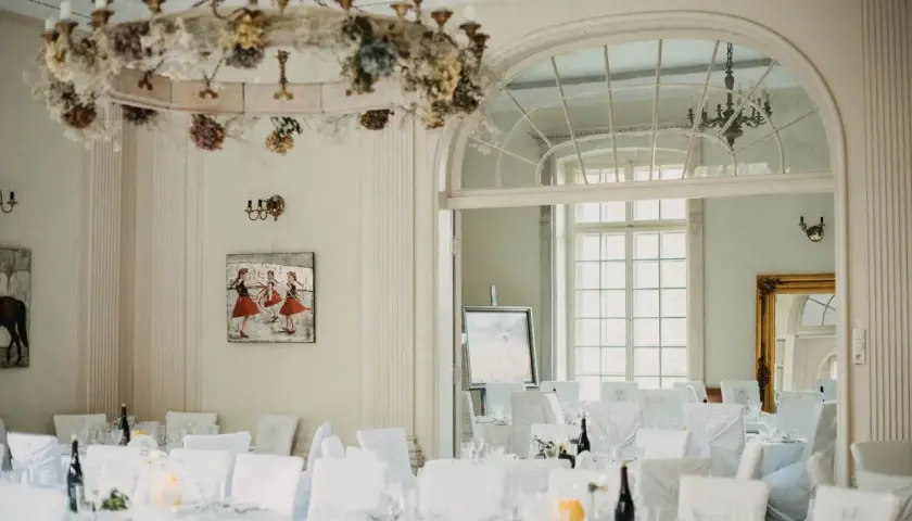 Elegancka sala bankietowa w pałacu Grąbkowo, udekorowana kwiatami i przygotowana na przyjęcie.