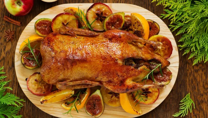 Pieczona kaczka w pomarańczach, jabłkach i figach, ozdobiona rozmarynem. Aromatyczne danie świąteczne.