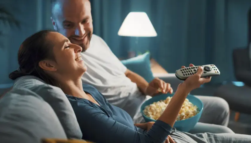 Para spędza miły wieczór, śmiejąc się i jedząc popcorn. Idealny czas na fajne filmy romantyczne na wieczór.