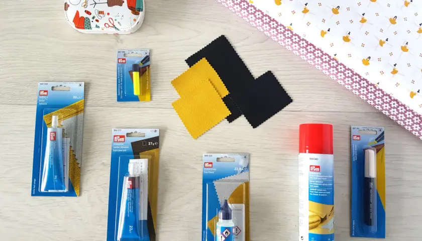 Matériel pour enlever colle sur tissu polyester : tubes de colle textile, cuir, spray adhésif, marqueur effaçable et tissu imprimé.