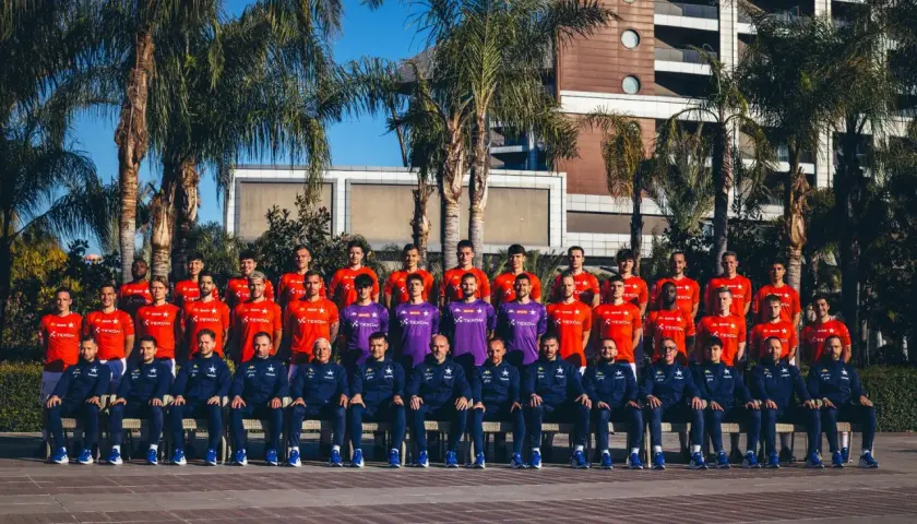 OGC Nice – zawodnicy pozują do zdjęcia w strojach sportowych na tle palmy i nowoczesnego budynku.