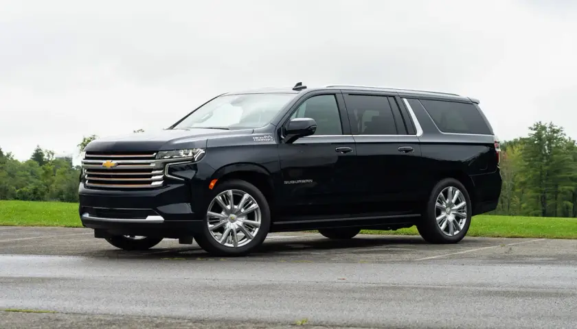 Czarny Chevrolet Suburban High Country z chromowanymi felgami stoi na parkingu.