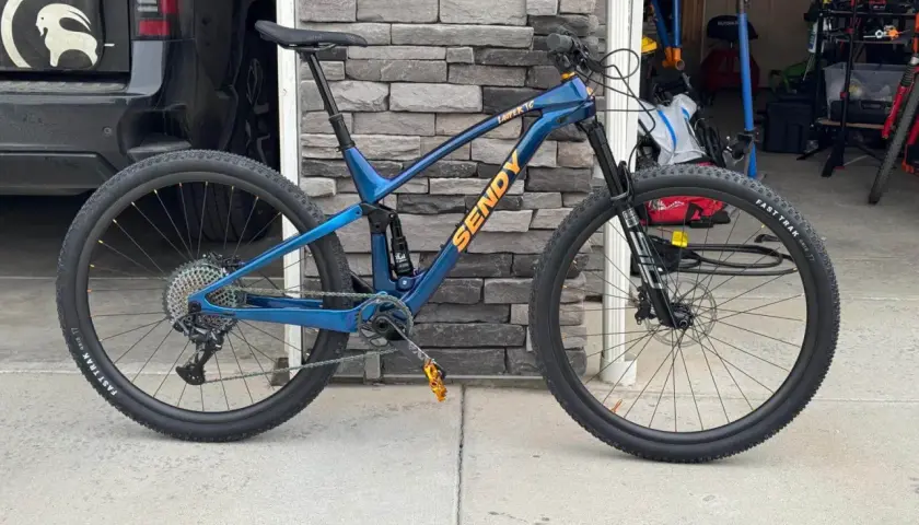 A blue Sendy mountain bike with full suspension, ready for any trail. Its robust mountain bike suspension system promises a smooth ride.