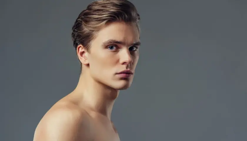 Joven con pelo liso hombre, ojos azules y piel clara, mirando a la cámara con expresión seria.
