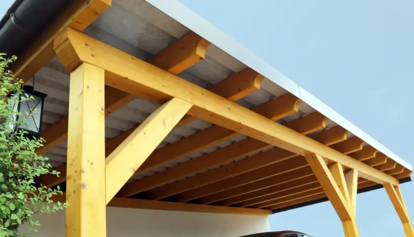 Detailansicht des Aufbaus eines Carport-Flachdachs mit sichtbaren Holzbalken und Dachpappe.