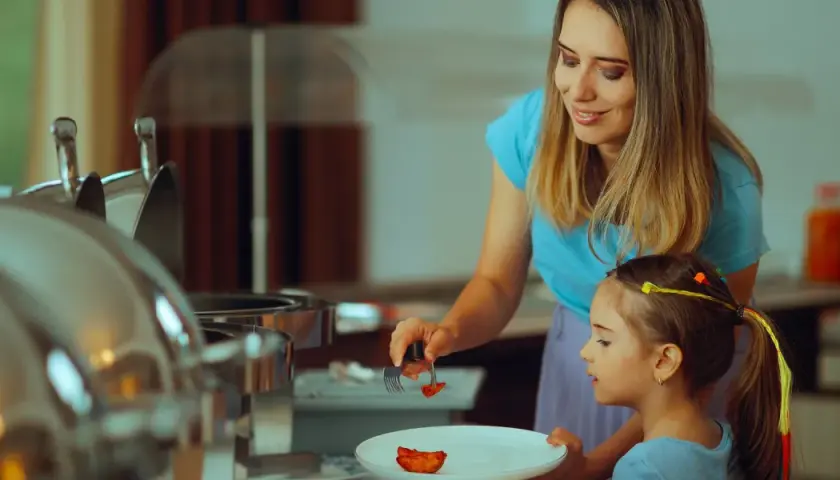 Mama pomaga córce nakładać jedzenie na talerz, stosując zasadę 80/20 diety.