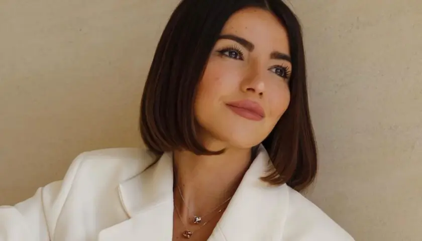 Mujer con un corte de pelo **italian bob**, blazer blanco y collares delicados.