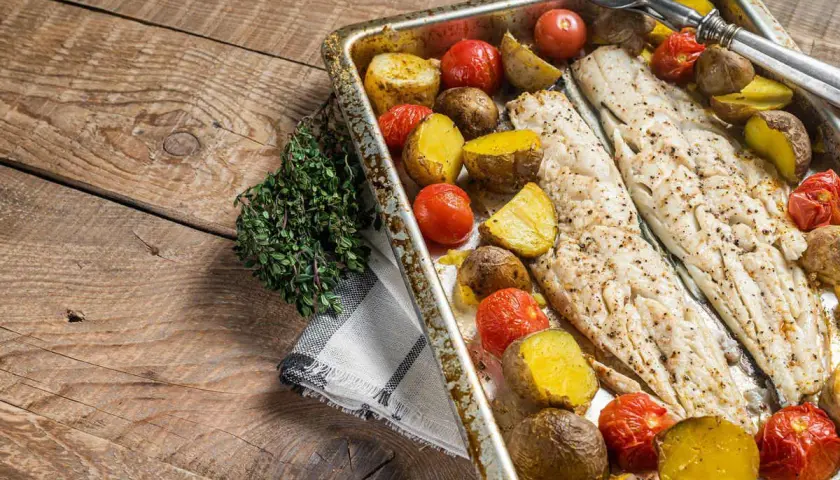 Coda di rospo al forno con patate e pomodorini, un piatto semplice e gustoso, pronto per essere servito.