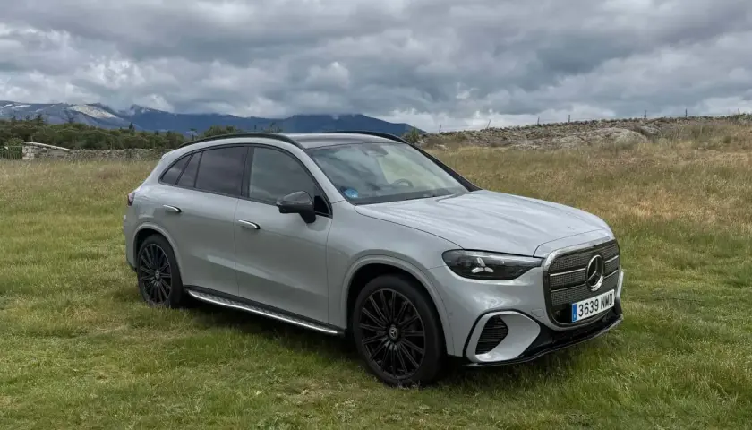 Un SUV gris moderno, con tracción 4 matic, descansa en un campo verde con montañas nubladas al fondo.
