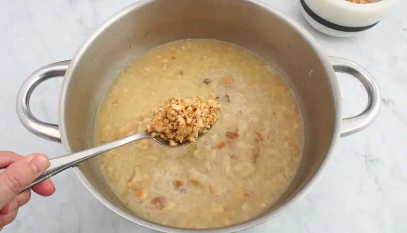 Cuchara con trozos de almendras listas para añadir a la olla, creando una deliciosa salsa de almendras.