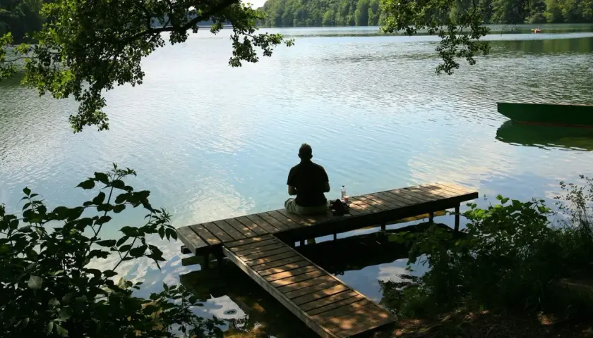 Mann sitzt auf Steg am See. Ein perfekter Ort, wo kann man in Deutschland Urlaub machen.