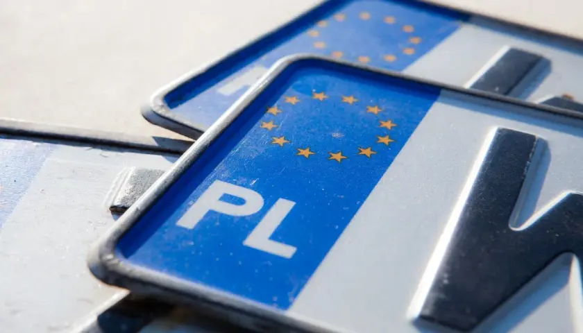 Zbliżenie na polskie tablice rejestracyjne z symbolem Unii Europejskiej. Widoczne litery "PL" i fragmenty numerów.