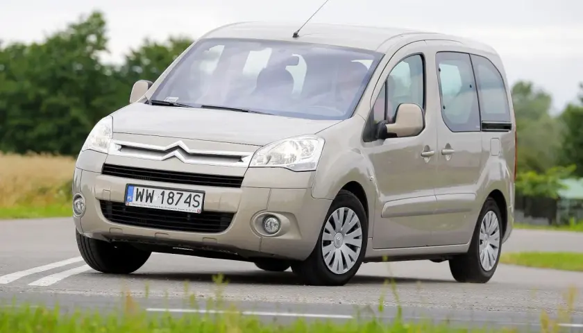Beżowy Citroen Berlingo 1.6 HDI z polskimi tablicami WW 1874S jedzie po drodze wśród zieleni.
