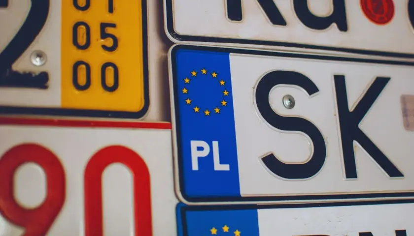 Zbliżenie na tablice rejestracyjne. Widoczne oznaczenia PL i SK, a także fragmenty innych tablic.