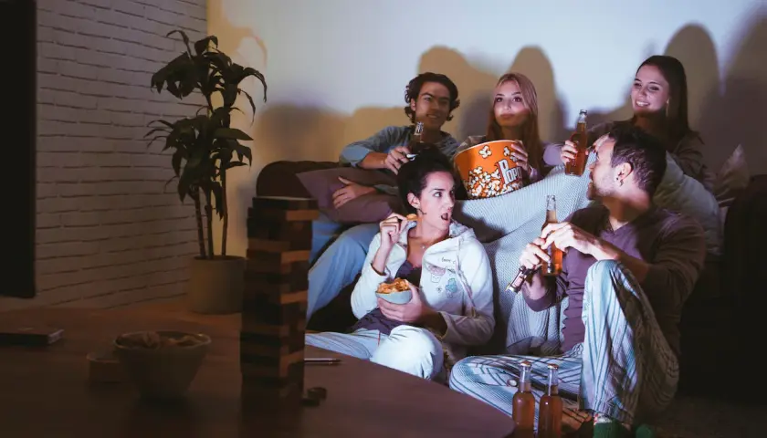 Ragazzi sul divano, popcorn e birra per una serata film.