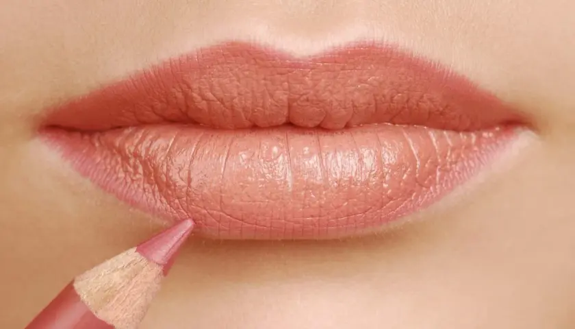 Dettaglio labbra con matita rosa che delinea il contorno per un effetto volumizzante. Scopri come ingrandire le labbra con la matita.