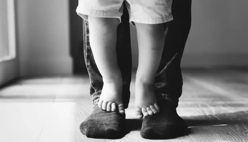 Piedini di bimbo su quelli del papà. Un abbraccio di gambe, un legame forte. Mia figlia preferisce il papà separato, ma i loro piedi uniti raccontano un amore che non si spezza.