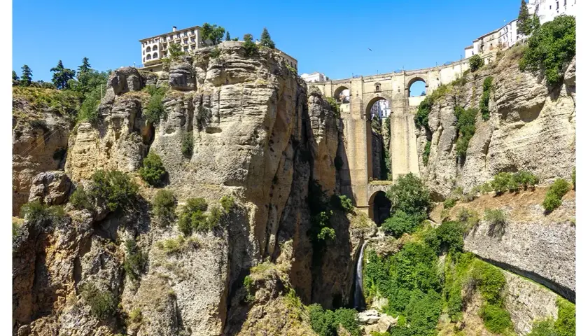 Impresionante Puente Nuevo sobre el Tajo de Ronda, un lugar imprescindible que ver en Ronda. Cascadas y edificios coronan los acantilados.