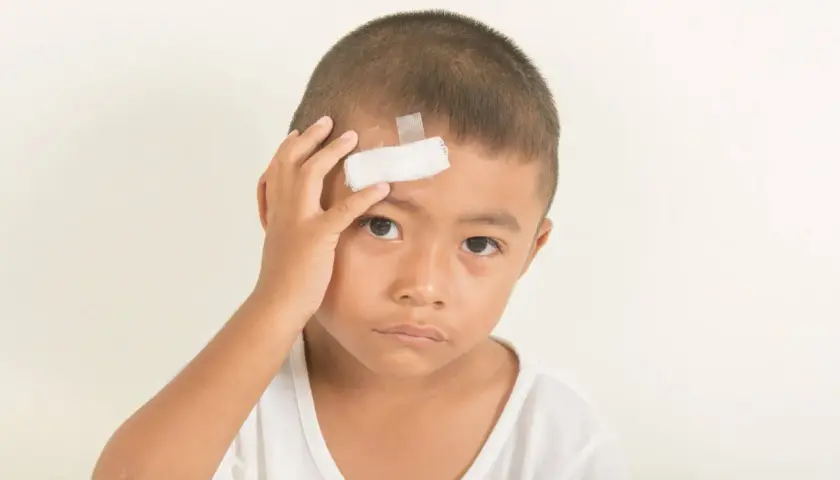 Bambino con cerotto sulla fronte, forse a seguito di un trauma cranico.
