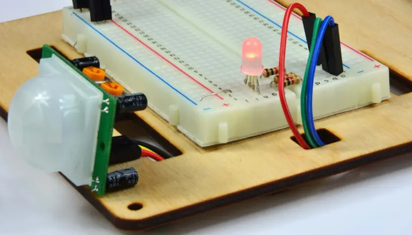 Czujnik ruchu PIR połączony z płytką styków i świecącą diodą LED. Ten kontaktron w oknie jest częścią projektu elektronicznego.